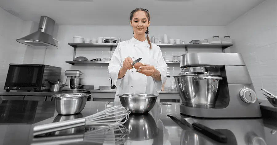 Mujer chef en una cocina rodeada de diversos equipos de cocina