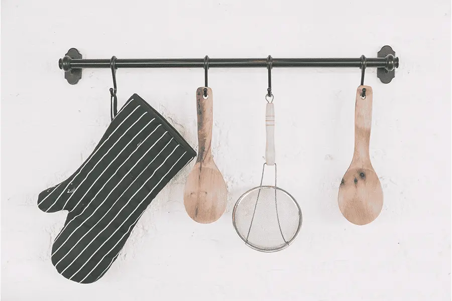 Ganchos y soportes en una pared de cocina sosteniendo algunos utensilios y accesorios de cocina