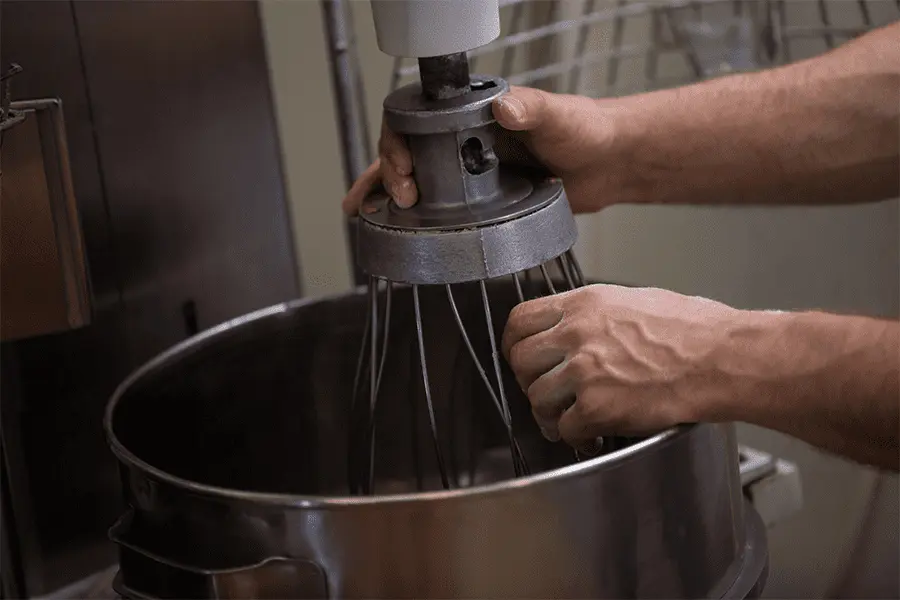 Manos de hombre quitando el globo batidor para limpieza aplicando uno de los consejos para mantener tus equipos de cocina