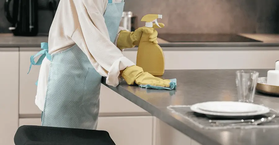 Mujer con delantal haciendo limpieza y desinfección en la cocina