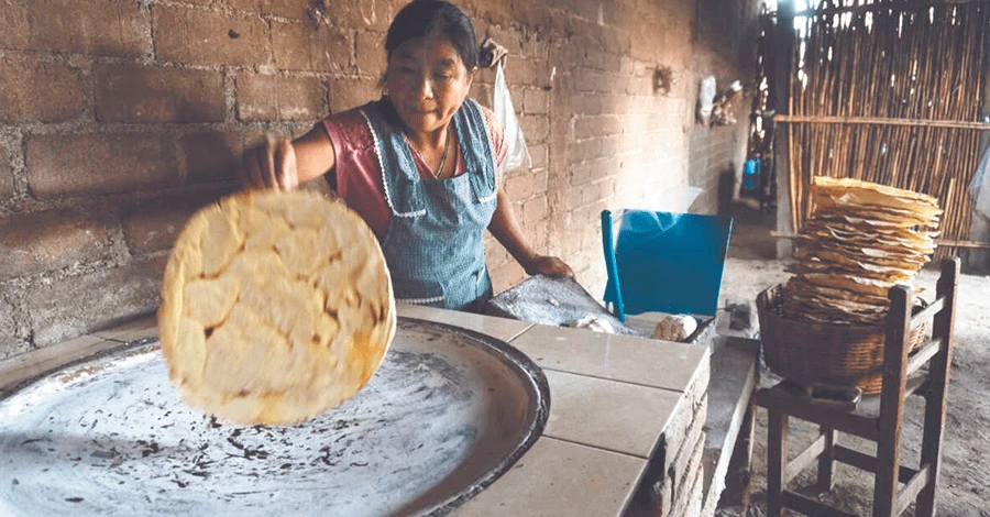 Mujer Oaxaqueña haciendo tortillas para tlayudas en comal en una cocina tradicional Oaxaqueña